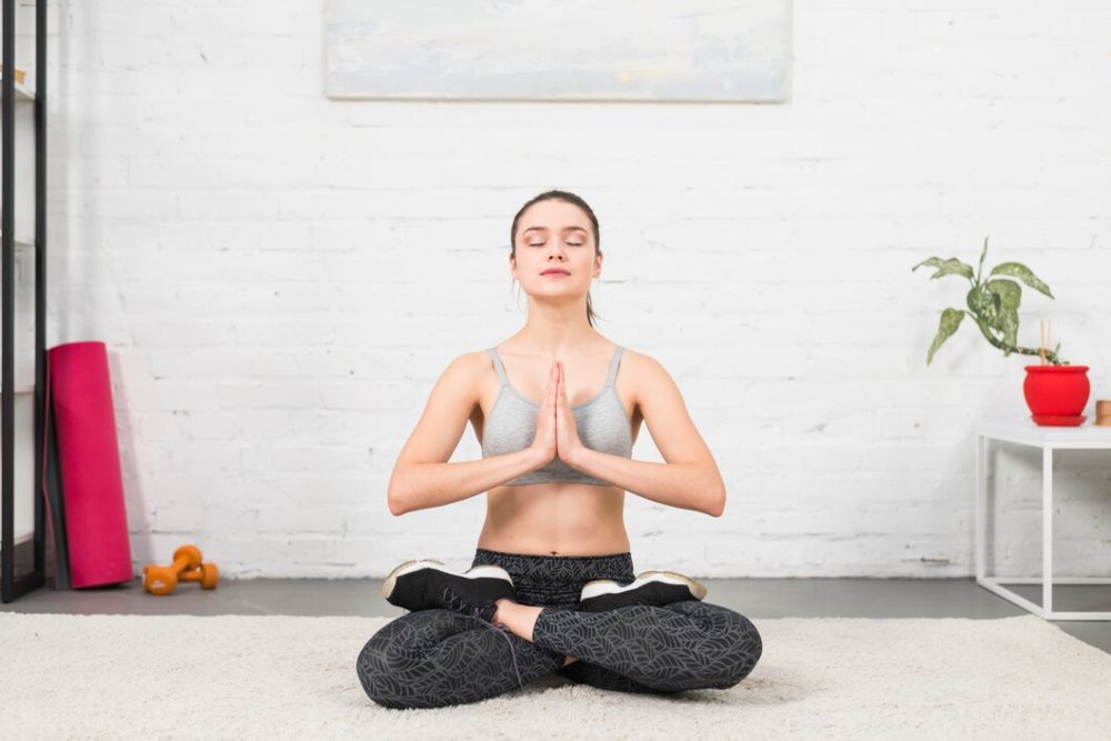 student performing ardha padmasana half lotus pose