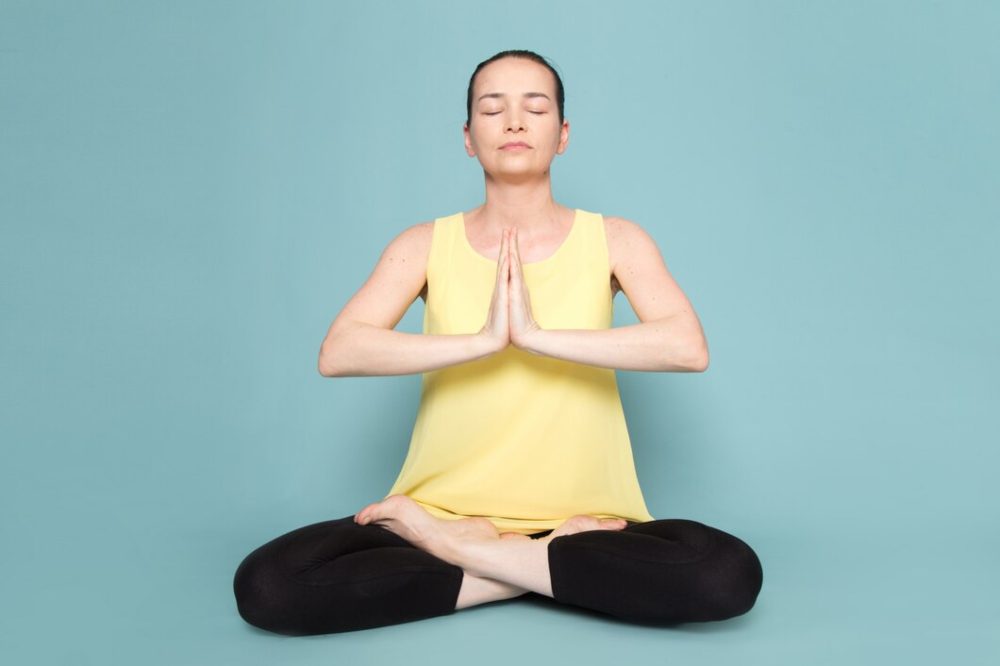 yoga teacher performing ardha padmasana