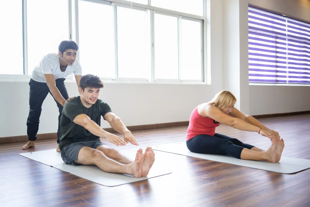 yoga instructor helping beginners with forward bend yoga instructor helping beginners with forward bend