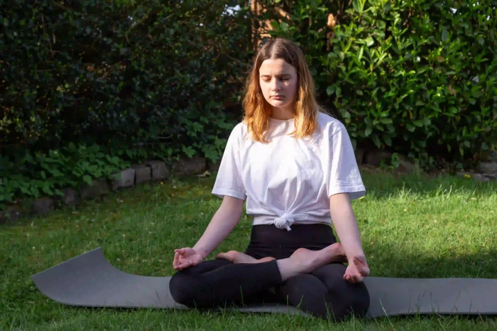 yoga practitioner meditating outdoors in a peaceful natural setting for mindful yoga practice