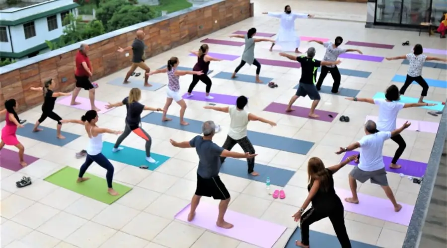 Group practicing yoga outdoors on colorful mats on a rooftop terrace